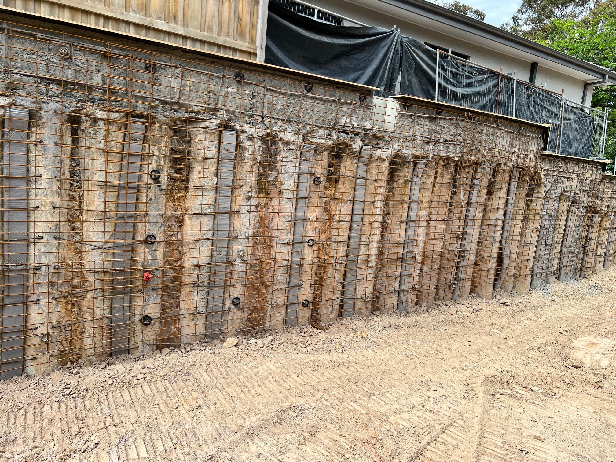 Concrete piling reinforcement cages installed for basement foundation in residential site with neighboring property