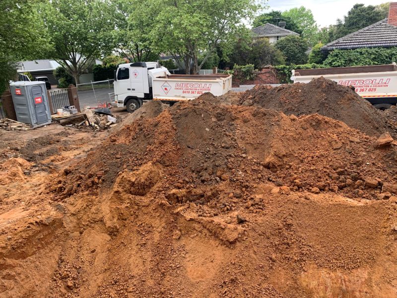 Northern suburbs excavation site showing characteristic red clay soil with earthmoving trucks in residential area