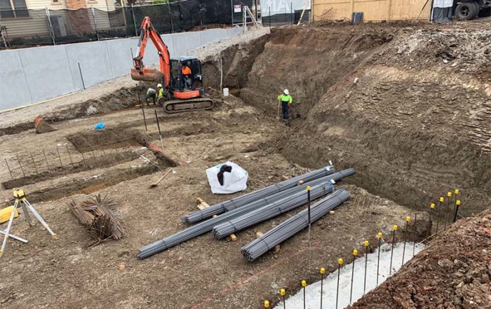 Bayside basement excavation showing drainage infrastructure installation with steel pipes and groundwater management in coastal soil conditions